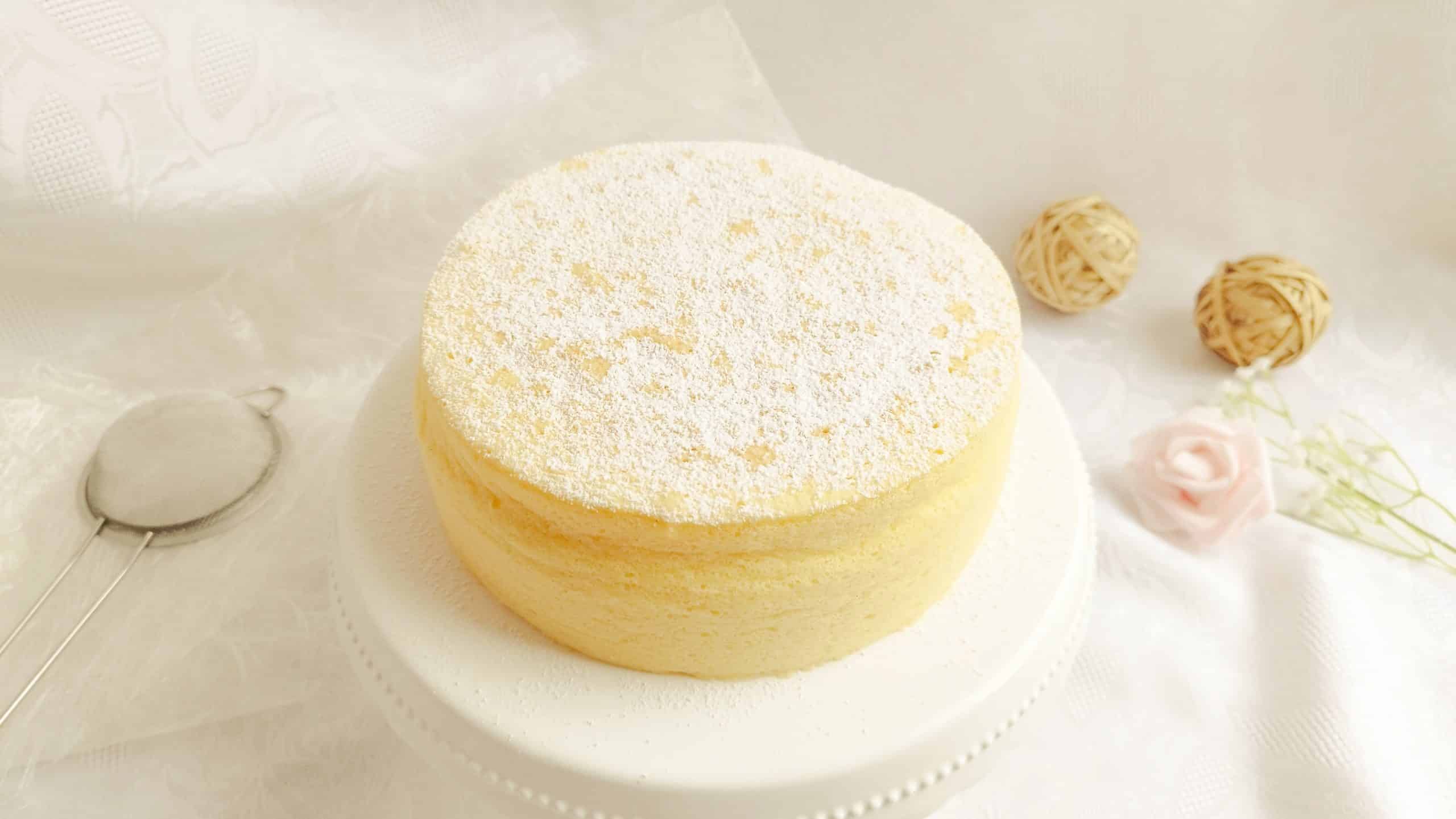 Japanischer Cheesecake auf einem Tortenteller mit Puderzucker bestäubt