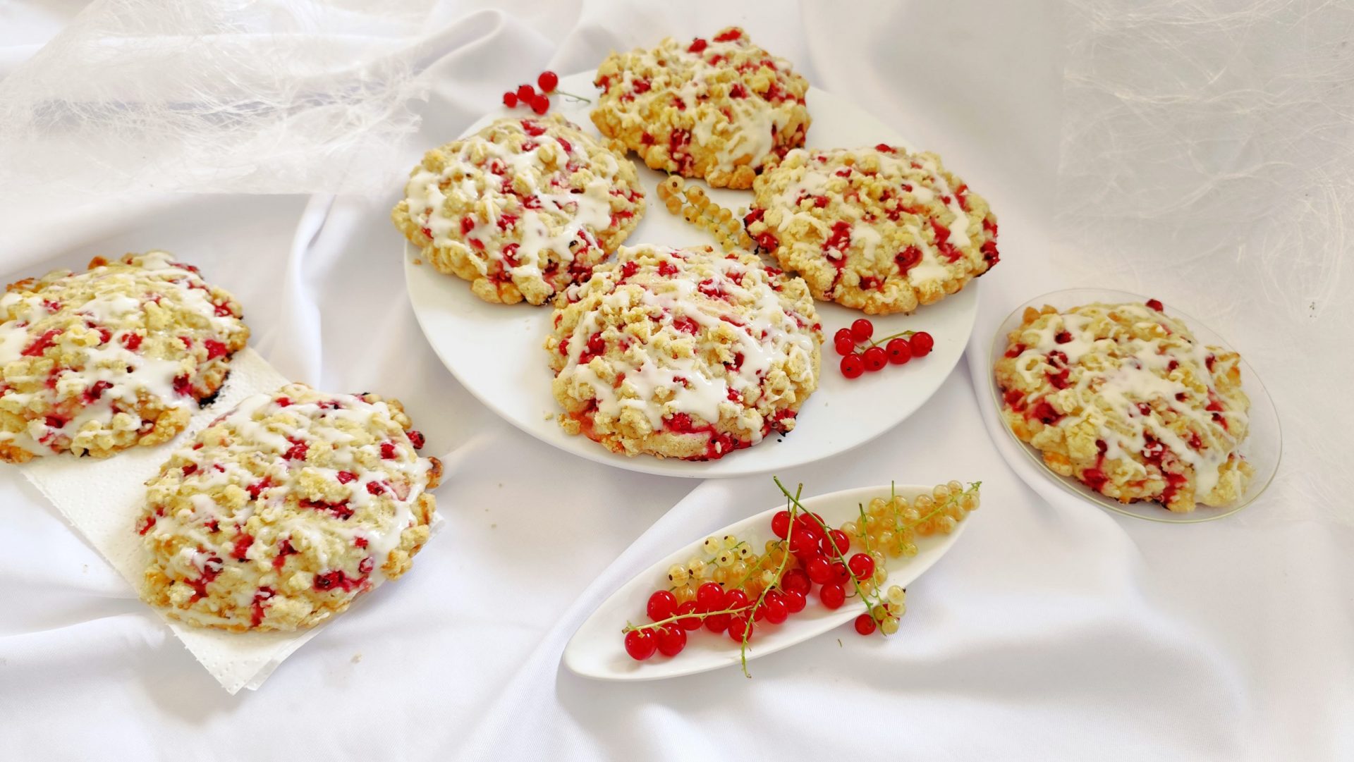 Rezept Streuseltaler mit Johannisbeeren angerichtet auf einem Teller und als Dekoartion Johannisbeeren